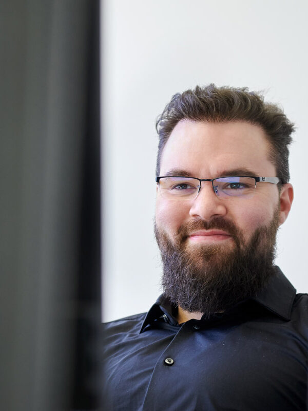 Freundliches Corporatefoto von Mitarbeiter einer Münchner IT Firma am PC