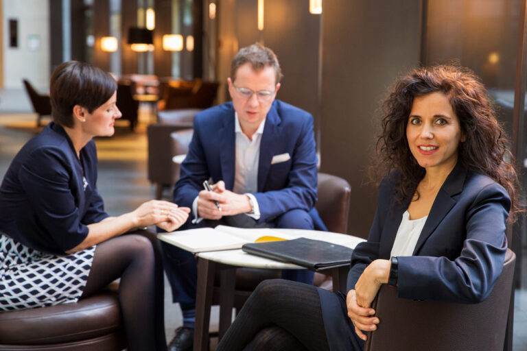 Authentisches Teamfoto für Unternehmen: kleines Team im entspannten Gespräch in einer modernen Lobby.