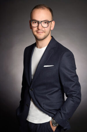 Selbstbewusstes Bewerbungsfoto eines Uhrenverkäufers vor minimalistim Hintergrund im Fotostudio München.