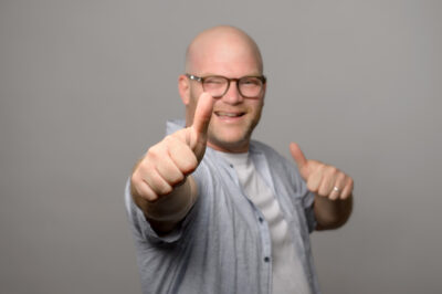 Dynamisches, positives Businessfoto von Psychologe im Fotostudio vor dezentem Hintergrund.