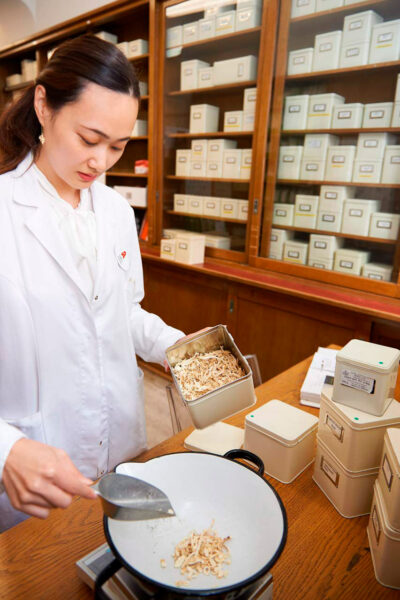 Stimmungsvolle Corporate Fotografie: Apothekerin beim Zubereiten von Kräutermischungen.
