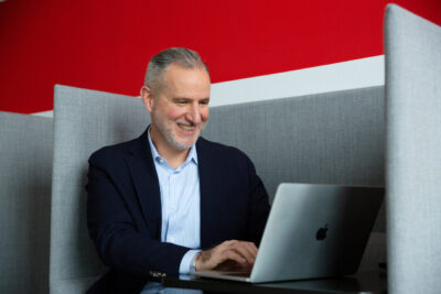Employer Branding Fotografie: konzentrierter Angestellter arbeitet lächelnd am Laptop.