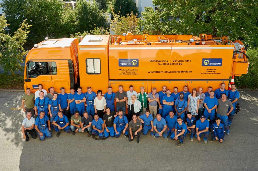Gruppenfoto von großem Team vor Lastwagen.
