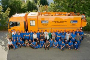Gruppenfoto von großem Team vor Lastwagen.