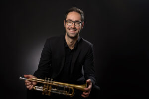 Klassisches Musikerportrait im Fotostudio München mit Trompete vor schwarzem Hintergund.
