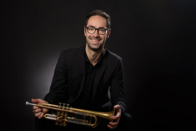 Klassisches Musikerportrait im Fotostudio München mit Trompete vor schwarzem Hintergund.