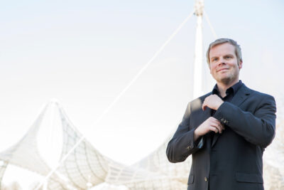Professionelles Outdoor-Businessportrait von Steuerberater vor urbanem Hintergund.