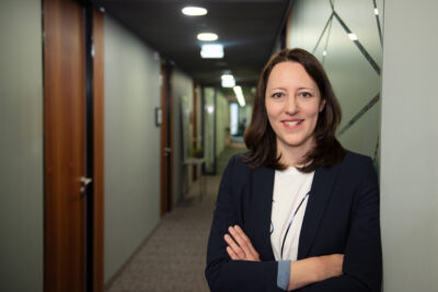 Modernes Personal Branding Foto einer Unternehmenberaterin. Im Hintergund ist unscharf die Flucht der Büroräumlichkeiten zu sehen.