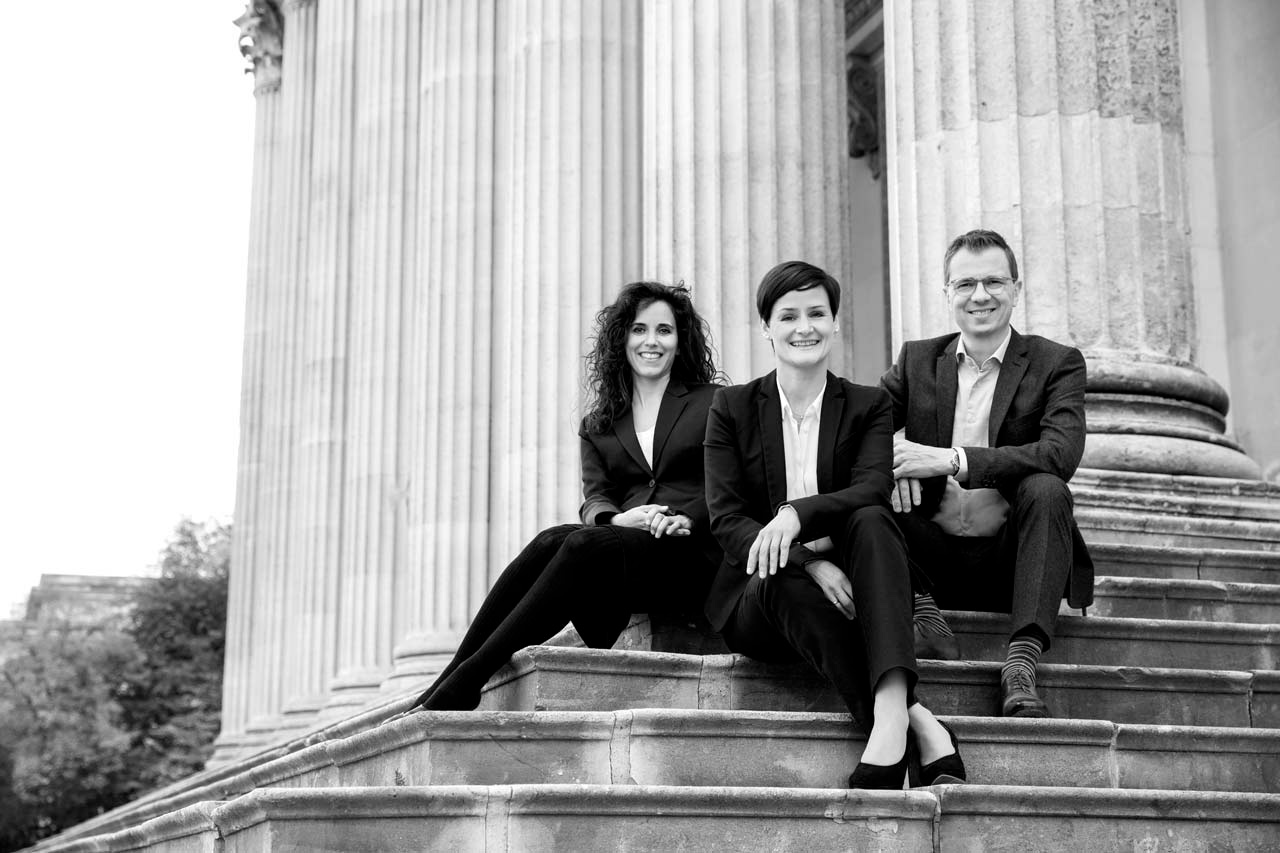 Natürliches Outdoor-Teamfoto in Schwarz-weiß von StartUp in der Finanzbranche mit klassizistischen Säulen im Hintergund