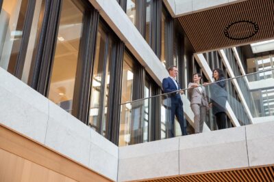 Corporate Fotografie vor moderner Architektur: Teamfoto eines Finanzstartups in einem modernen Bürogebäude in München mit spannender Perspektive fotografiert.