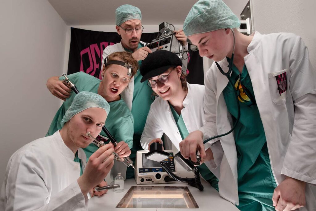 Kreatives Bandfoto mit der Band Defibrüllator in OP-Kitteln und diversen medizinischen Utensilien